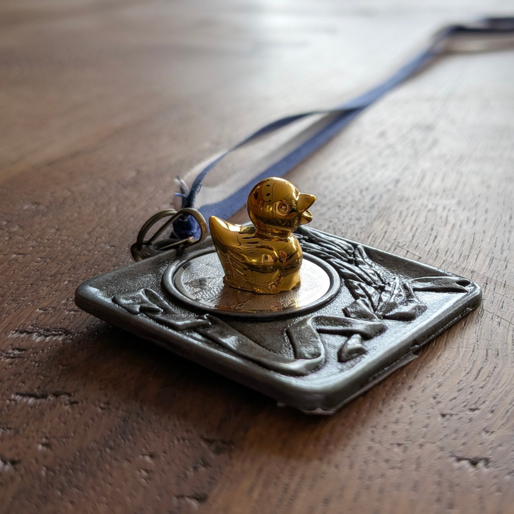 Glimmend goudkleurig verstopeendje op een medaille van The Lovely Club